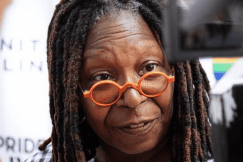 A photo taken by Jordan Star of actress Whoopi Goldberg wearing orange glasses on a red carpet.
