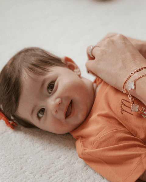 A Mom changing her very happy baby's bubuleh shirt.