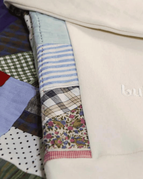 the upcycled quilted crewneck showing the embroidered "bubuleh" logo in white on top of a quilt.