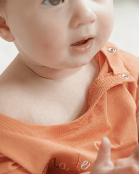 A closeup shot of the mini anxie-tee showing two metal snap up buttons on the shoulder for each changing.