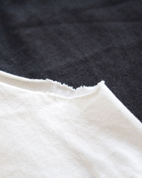 A photo of the new 2023 faygeleh tank top in white with the handwritten word faygeleh in Yiddish and english, showing the distressed armholes.