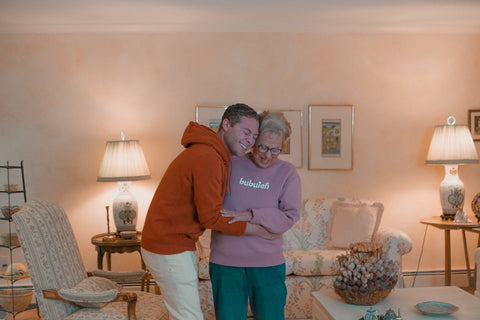 bubuleh founder and CEO Jordan Star hugs his grandma, laughing, while wearing a cinnamon bubuleh hoodie.