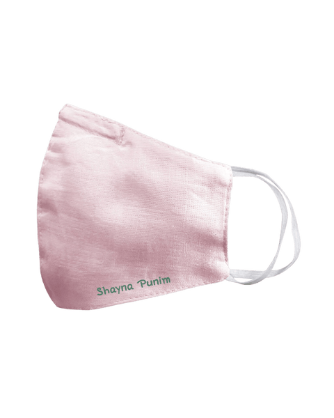 A light pink linen face mask that says shayna punim embroidered in maroon on the bottom left.