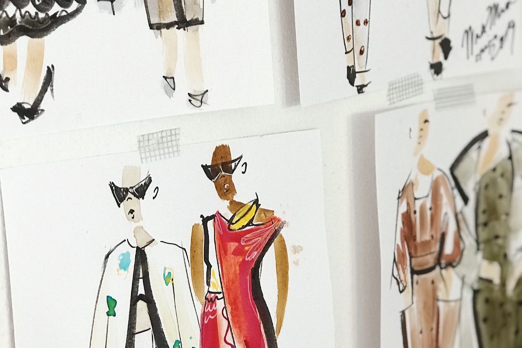 A montage of fashion illustration sketches showing different female models in Spring-inspired designs that are pinned against a wall.