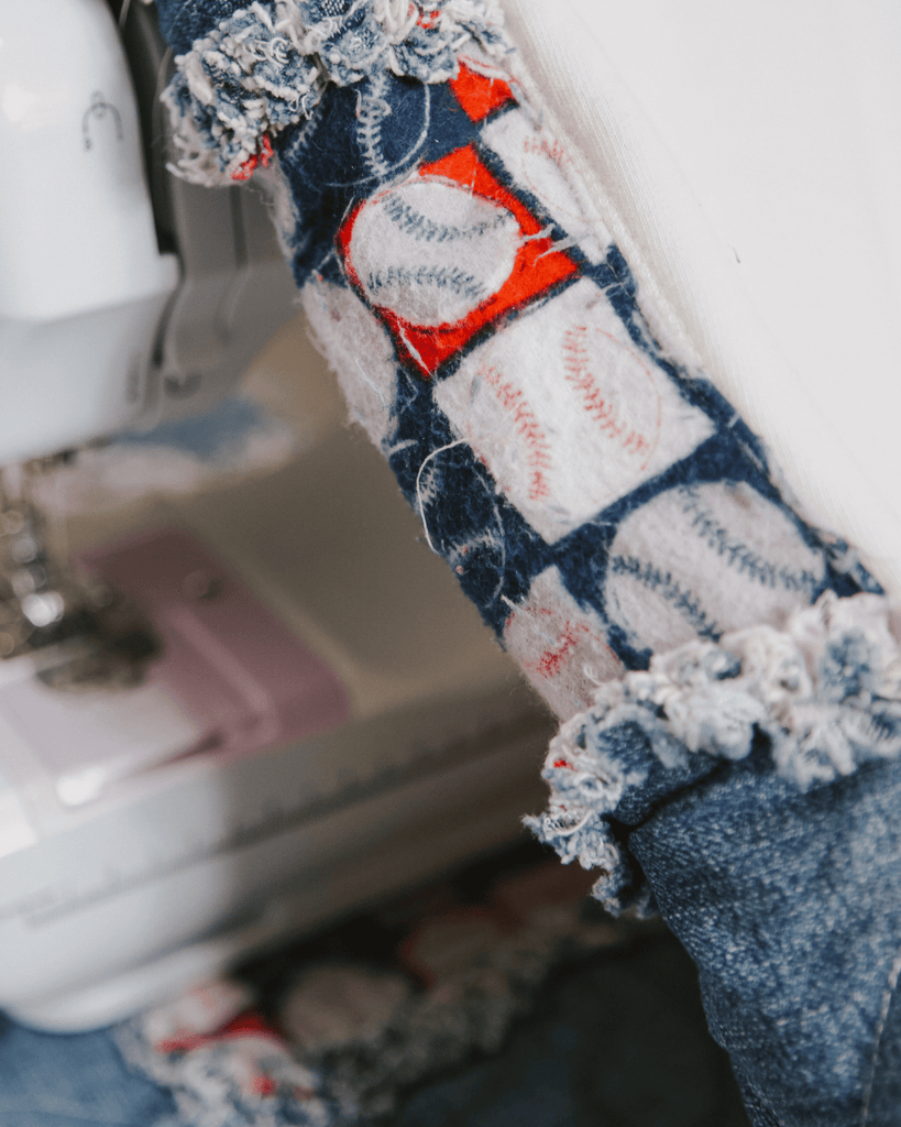 A small pink sewing machine stitching machine stitching denim fabric closeup.