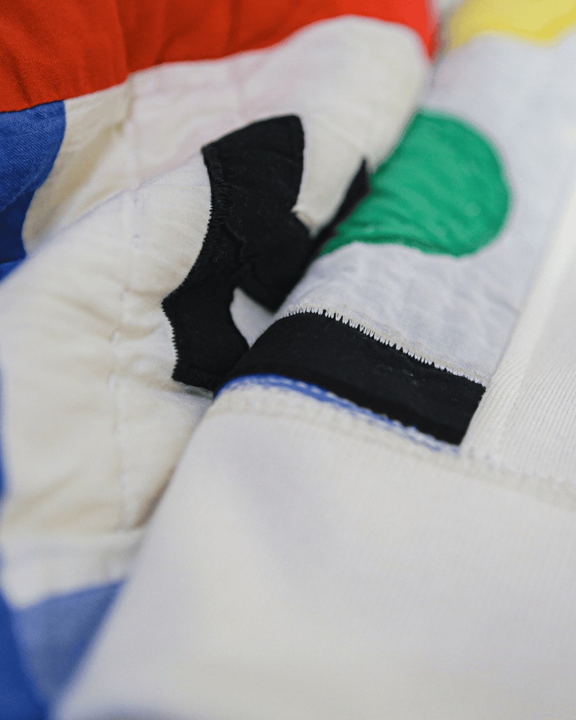 A closeup detal of the Joyride Crewneck stitching and quilted red, yellow, green and blue fabric.