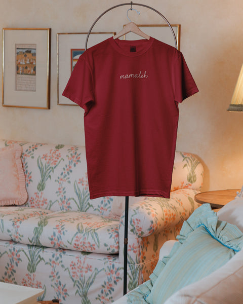 A photo of a maroon t-shirt on a vintage valet stand with the word "mamaleh" embroidered on front.