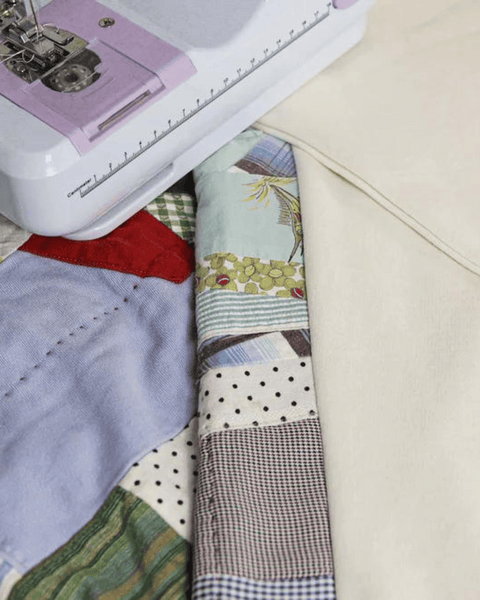 A sewing machine on top of the vintage fabric showing New England colors and Spring patterns.