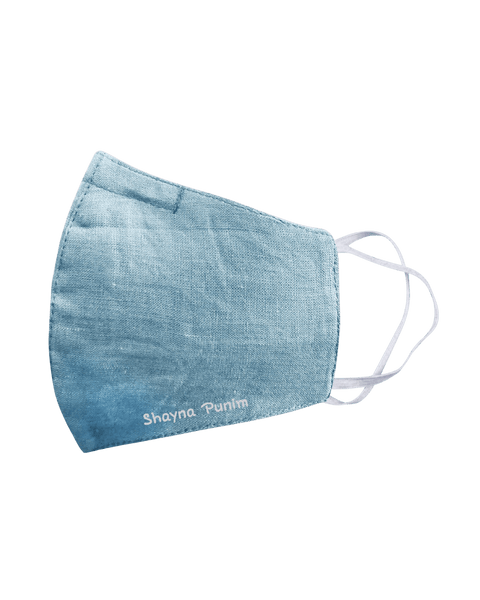 An aqua blue spring linen face mask that says "shayna punim" embroidered on the bottom, with white ear loop straps.