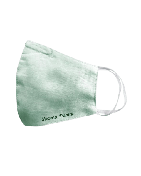 A mint green spring linen face mask that says "shayna punim" embroidered on the bottom, with white ear loop straps.