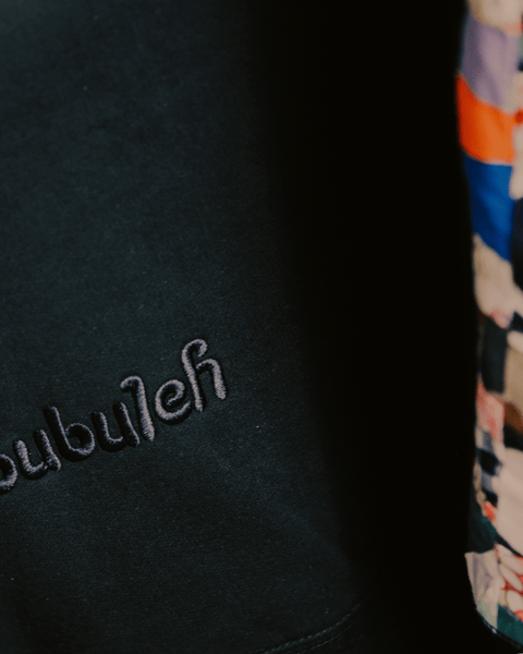 A black sweater with crazy quilting on the side and bubuleh embroidered.
