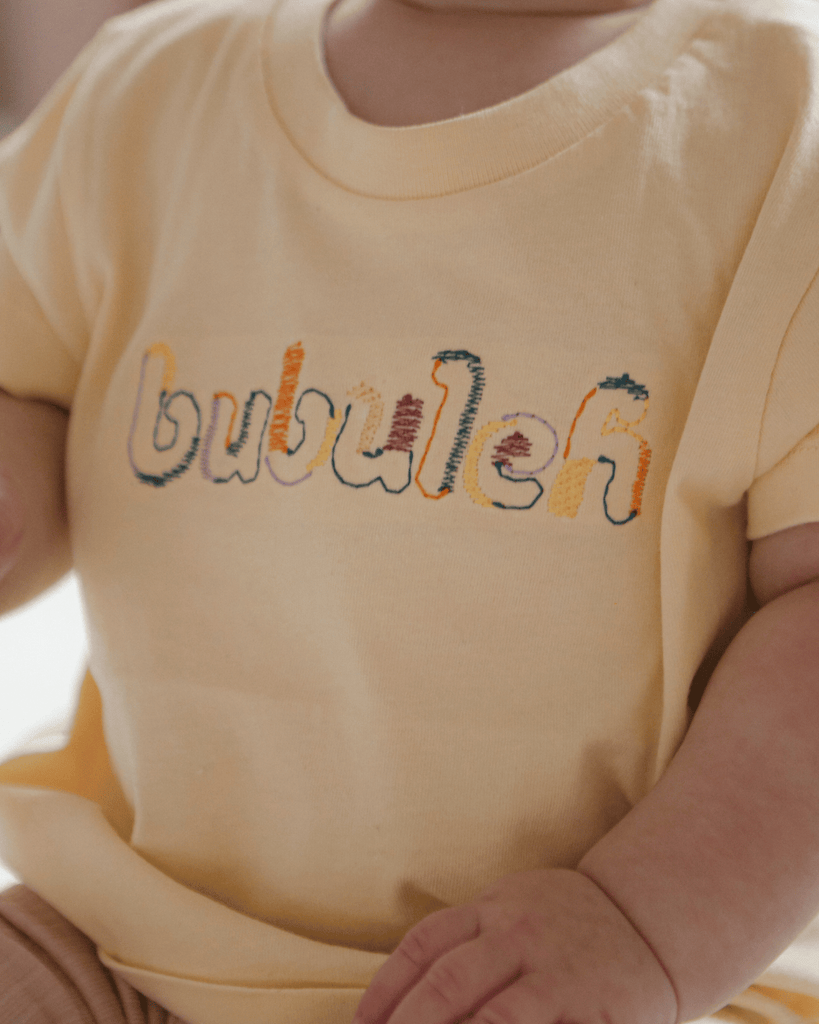 Unique baby embroidery on a newborn girl in a Boston nursery.