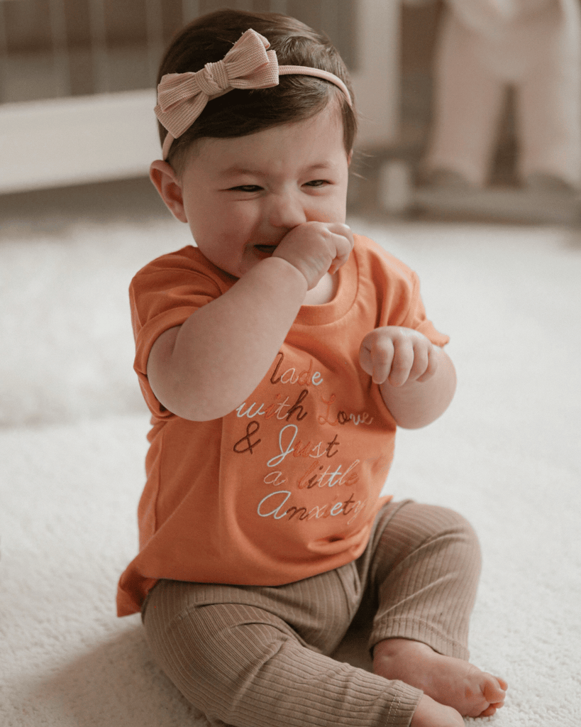 A baby laughing in a orange / pumpkin bubuleh mini anxie-tee.