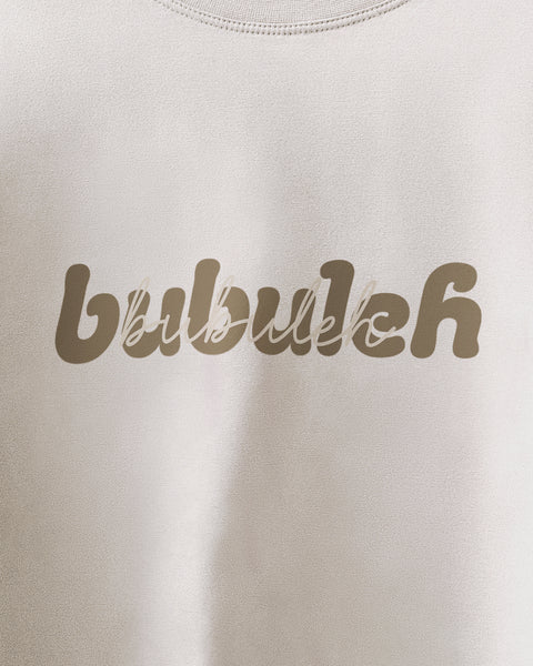 A closeup of a white unisex t-shirt showing the bubuleh logo in retro bubble letters with script saying bubuleh written over it.