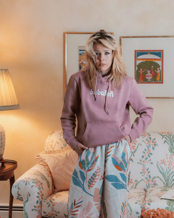 A blonde mail looks directly into the camera while wearing a lavender bubuleh hoodie.