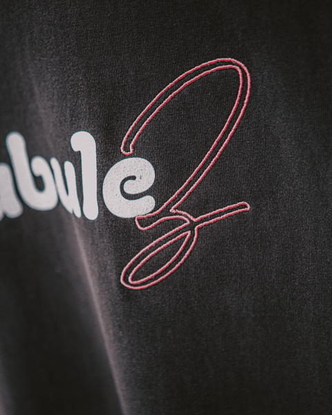 A closeup photo of a black vintage black shirt showing an embroidery pink "z" that spells out bubulez.