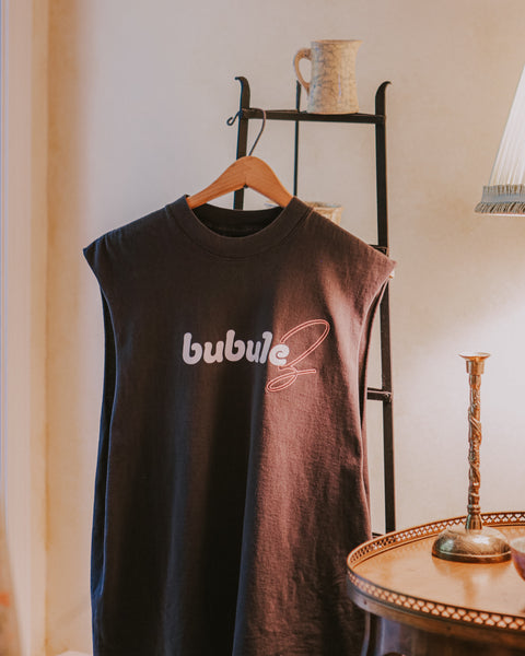 The bubuleh bubulez tank top hanging on a rack in a Grandma's living room lit by a warm lamp.