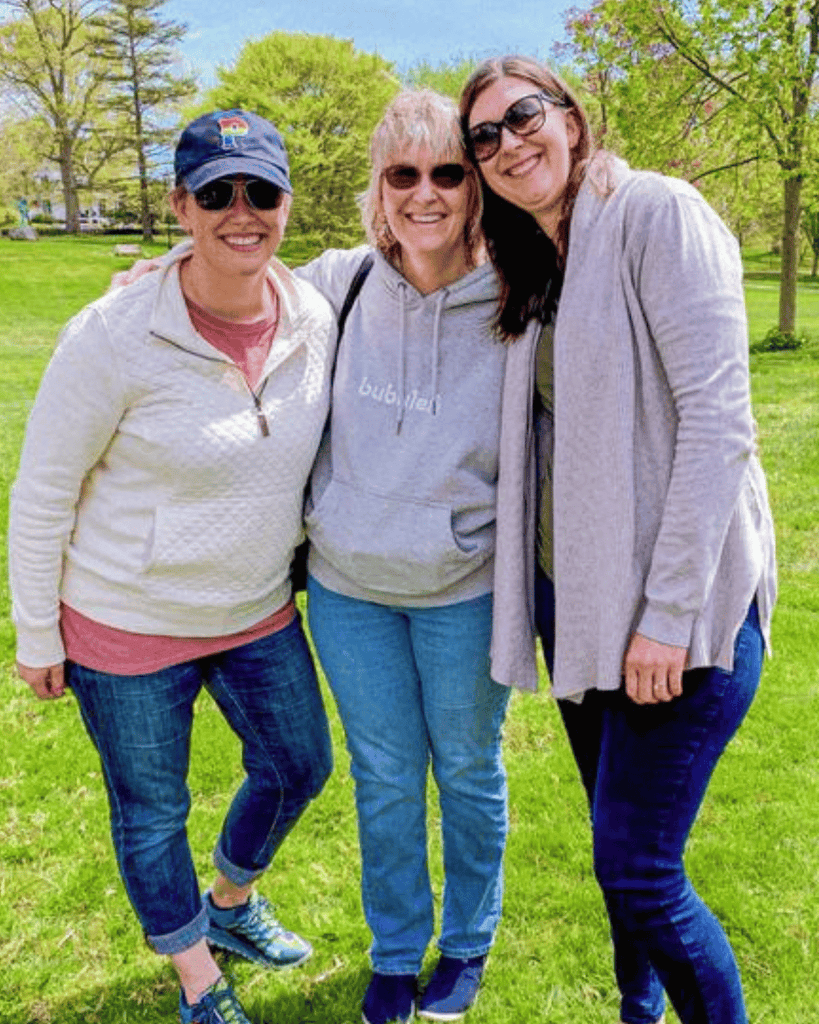 A mom and her two daughers wearing a bubuleh hoodie and Boston baseball hats.