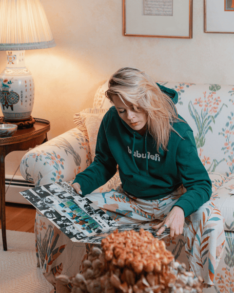 A blonde model wearing a green bubuleh hoodie while looking at a vintage Crosby Stills and Nash album.